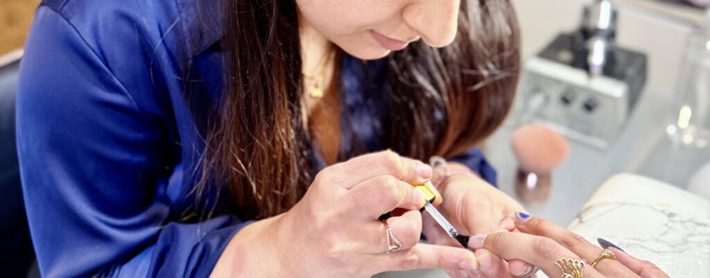 Nail technician applying polish during a manicure at Beauty With Grace